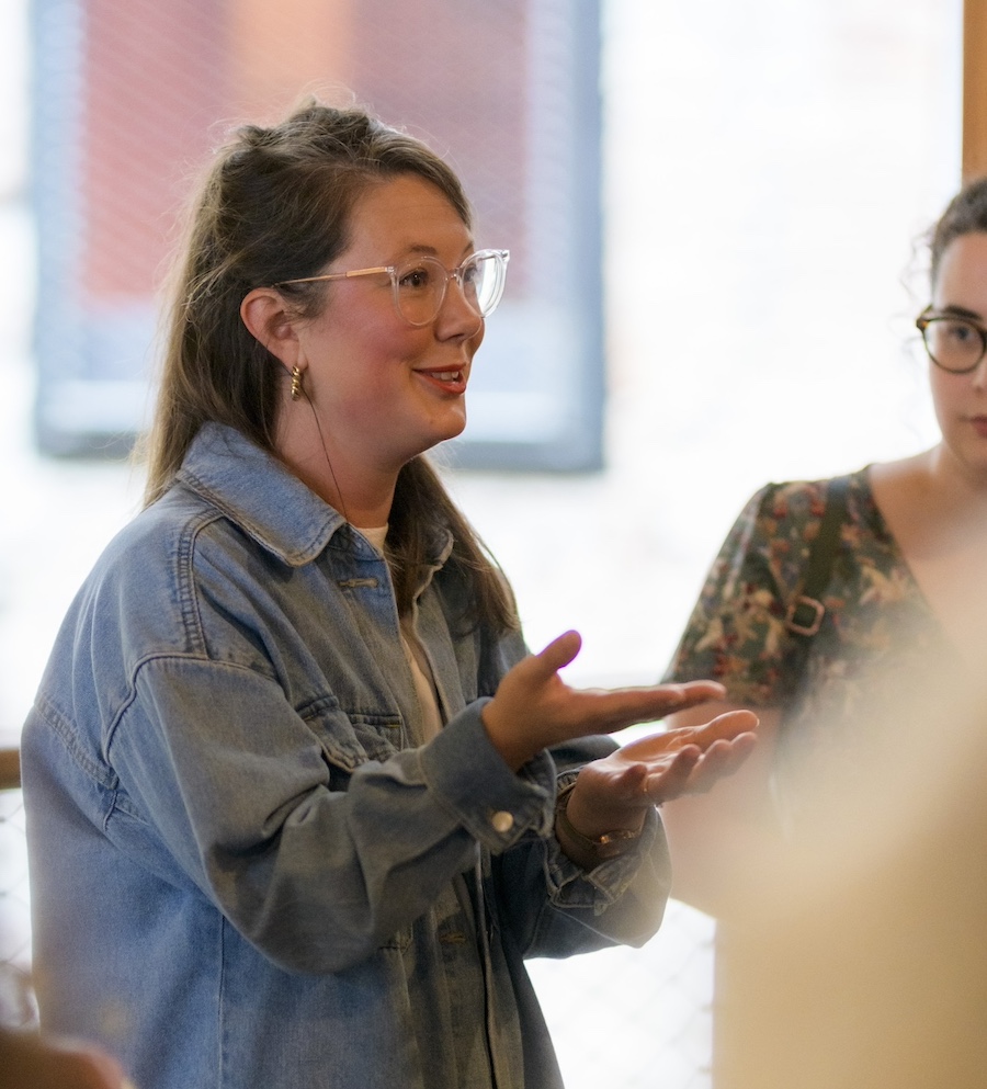 Photo of Emily Williams, the Executive Associate of Beyond Face, smiling and talking to someone out of frame whilst explaining something and using her hands to gesture