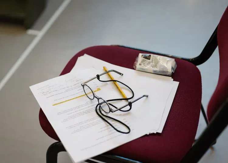 A script for a play rests on a chair with a pair on glasses ontop