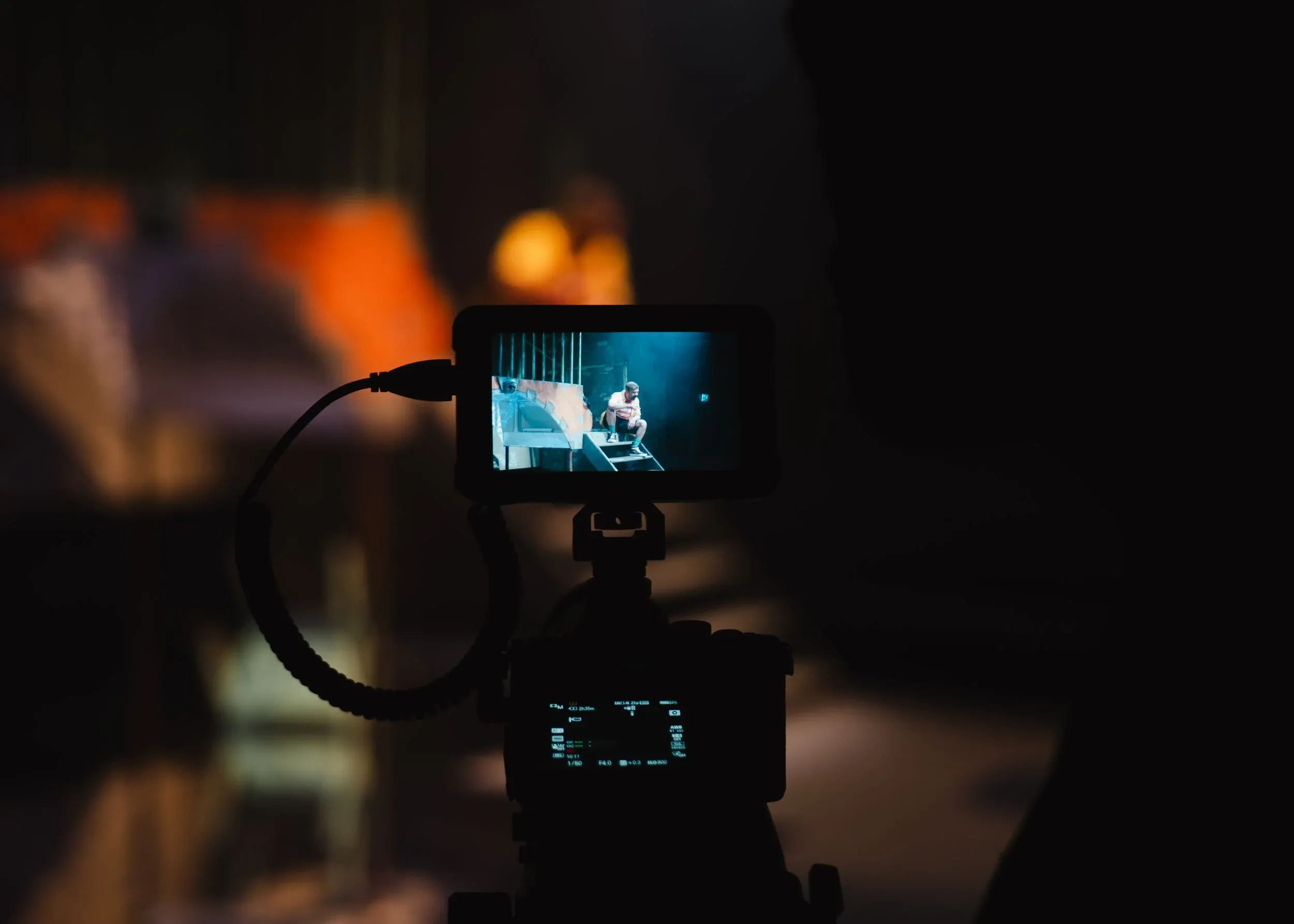 A camera records a performance on a stage in the distance