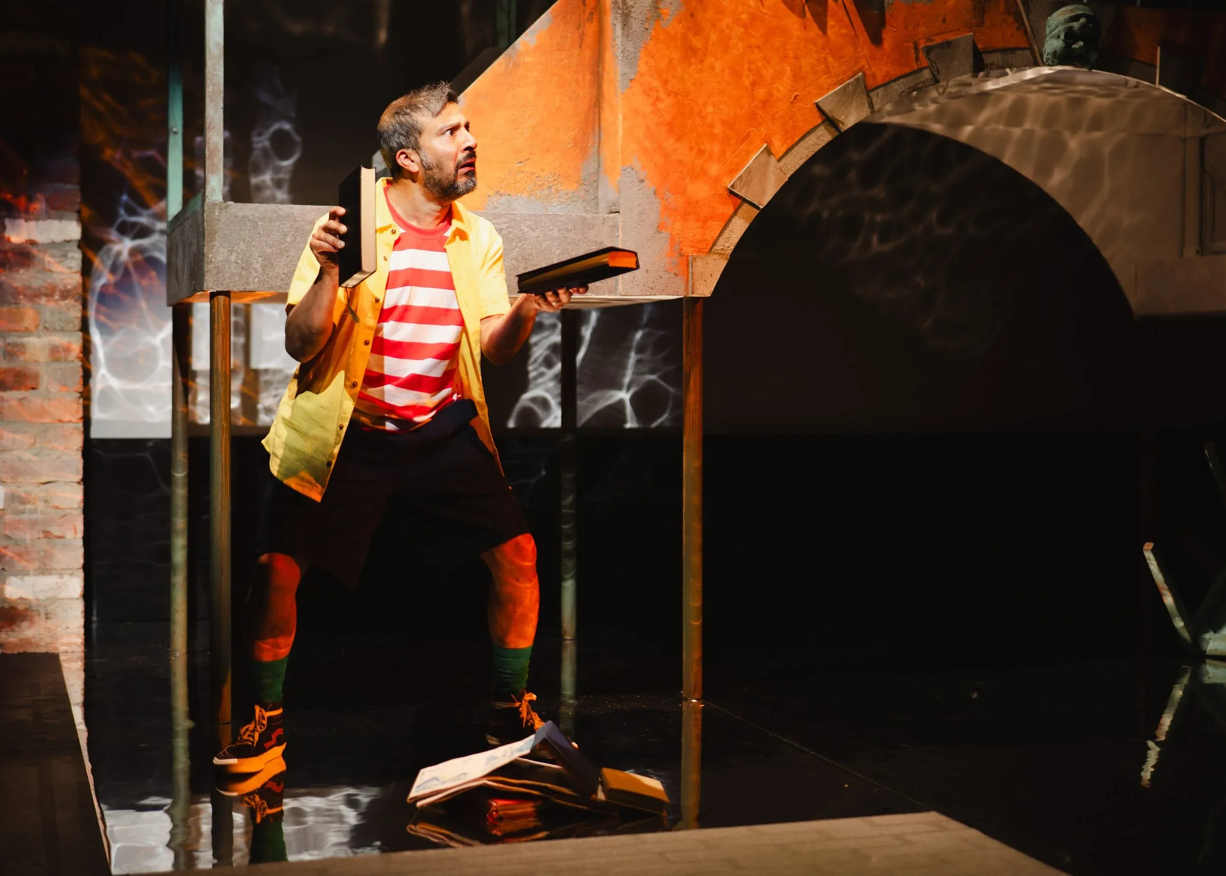 A man is dressed in a red and white striped shirt with a hat on, he is on a stage performing