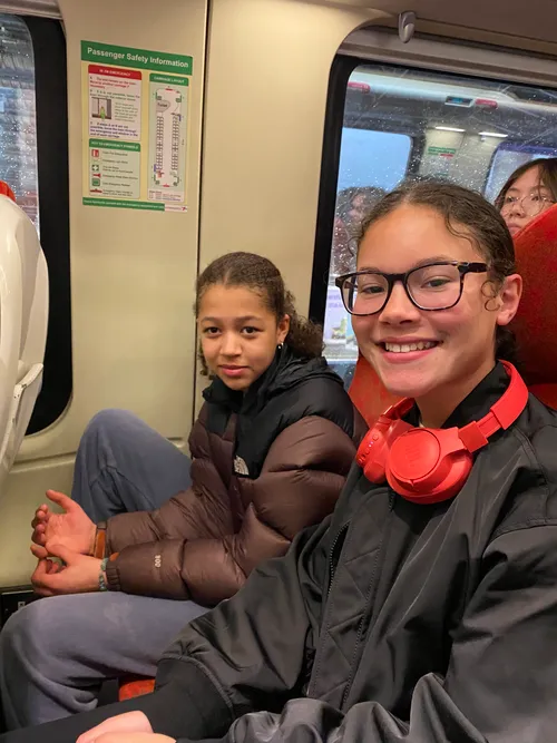 Two girls sit on a train smiling