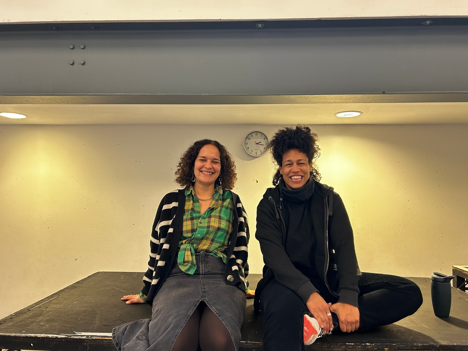 Two woman sit next to eachother smiling