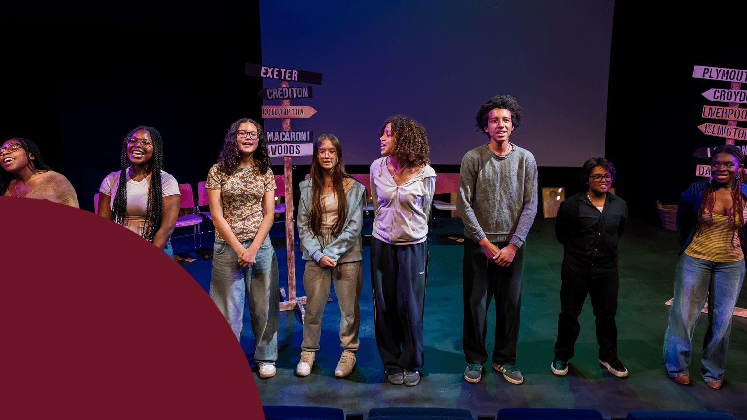 Eight young people stand on stage