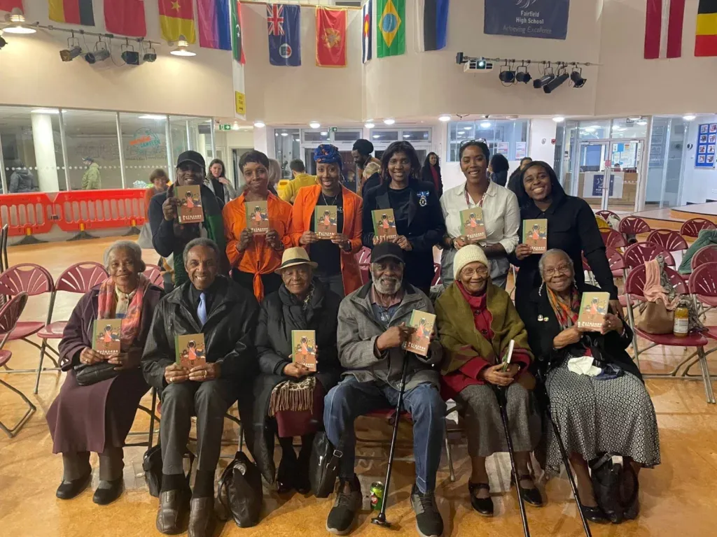 A group of black elders are holding the same book smiling at the camera